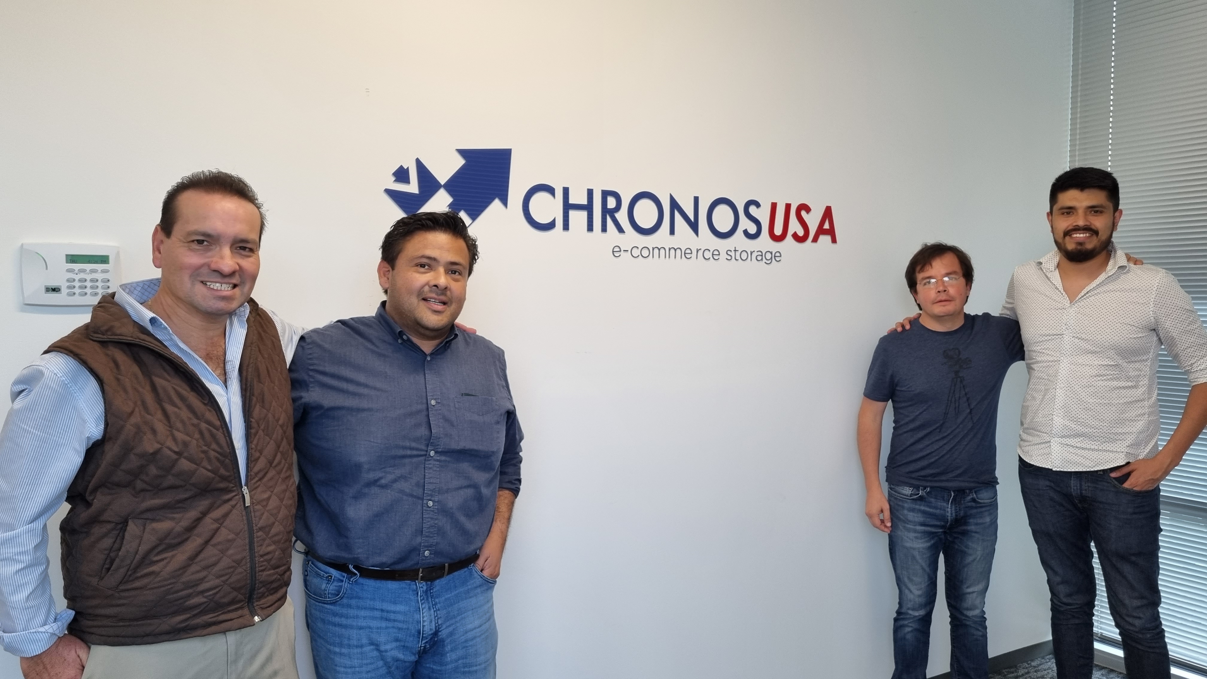 Equipo de Chronos USA frente al logo de la empresa